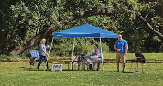 stock photo of ozark trail canopy set up in park with people under it