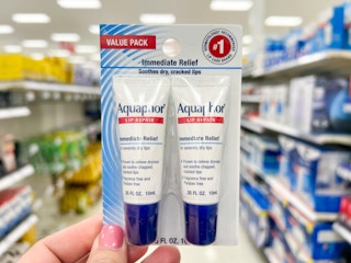 hand holding up two pack of Aquaphor lip balm inside Target