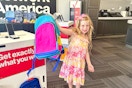 a child holding up a backpack in verizon