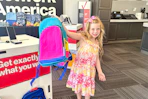a child holding up a backpack in verizon