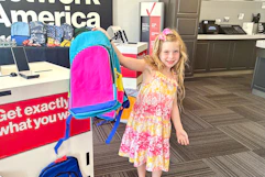 a child holding up a backpack in verizon