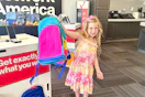 a child holding up a backpack in verizon
