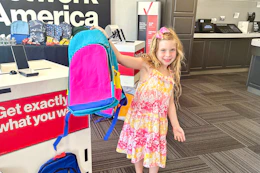 a child holding up a backpack in verizon