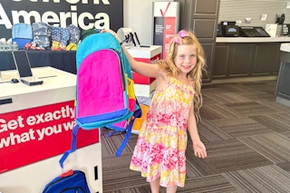a child holding up a backpack in verizon