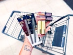 hand holding makeup items above walgreens cart