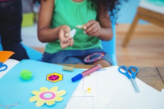 A little girl doing crafts at a take with paper and stickers out