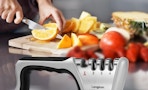 a knife sharpener next to a cutting board with food 