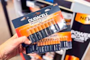 hand holding two packs of duracell batteries