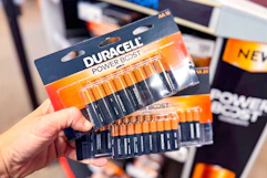 hand holding two packs of duracell batteries