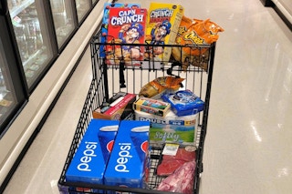 A cart with groceries in a store aisle.