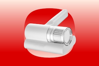 A white handheld bed vacuum with a brush roll about 5 inches wide and a short hand handle