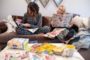 Two women sitting on a couch browsing Black Friday holiday sales ad while eating popcorn.