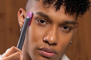 A man using a red light therapy device on his skin