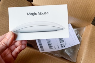 Apple magic mouse and return label next to a shipping box.