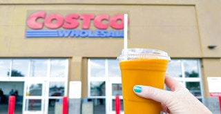 person holding a mango smoothie from costco near entrance