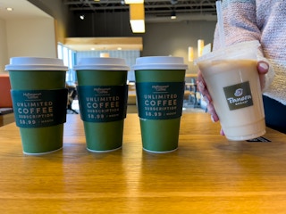 4 cups of coffee, one iced, on a table inside Panera