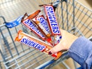 4 Snickers candy bars held up over Walmart shopping cart