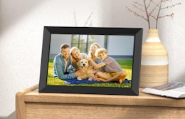 A picture frame with a family photo on a wooden dresser