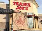 a person holding a trader joe's bag outside trader joes