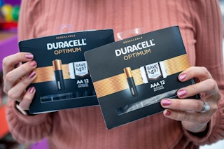 A person holding packages of Duracell Optimum batteries
