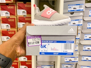 someone holding an adidas kids shoes with shoe box