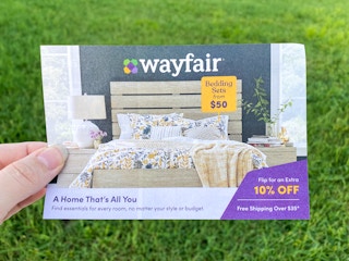 a hand holding the edge of a wayfair mailer coupon for 10% off