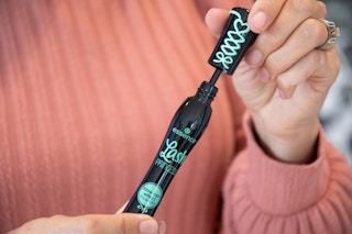 a person opening a tube of mascara