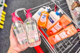 hand holding garnier face wash over a shopping cart with dial, lubriderm, and suave products