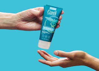 a hand giving another hand a tube of hand cream