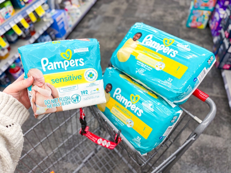 person holding pampers wipes by diaper packs in a cart