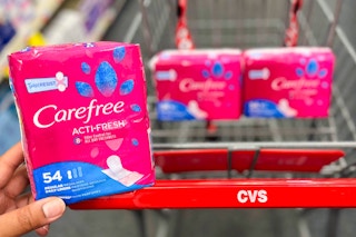 hand holding pack of Carefree liners in front of shopping cart with two more packs inside