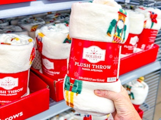 hand holding a holiday time christmas throw in front of display at walmart