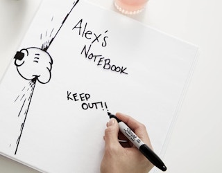 a person writing on a notebook with a Sharpie