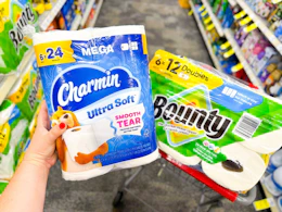 hand holding charmin toilet paper and bounty paper towels in a cvs cart