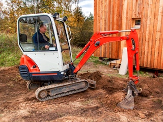 a person on a mini excavator on a construction site digging up dirt
