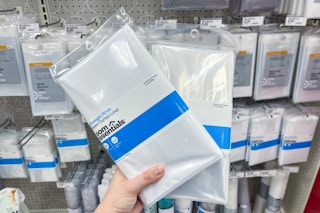 hand holding 2 room essentials shower liners in front of a target shelf