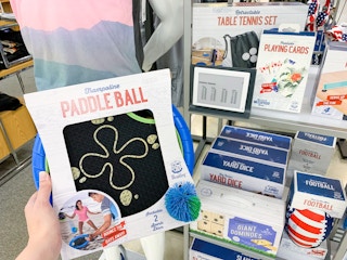 someone holding paddle ball game box in front of outdoor game display in stores at kohl's