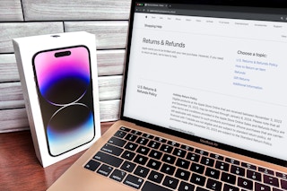 an apple iphone next to a macbook displaying the return policy for the apple store