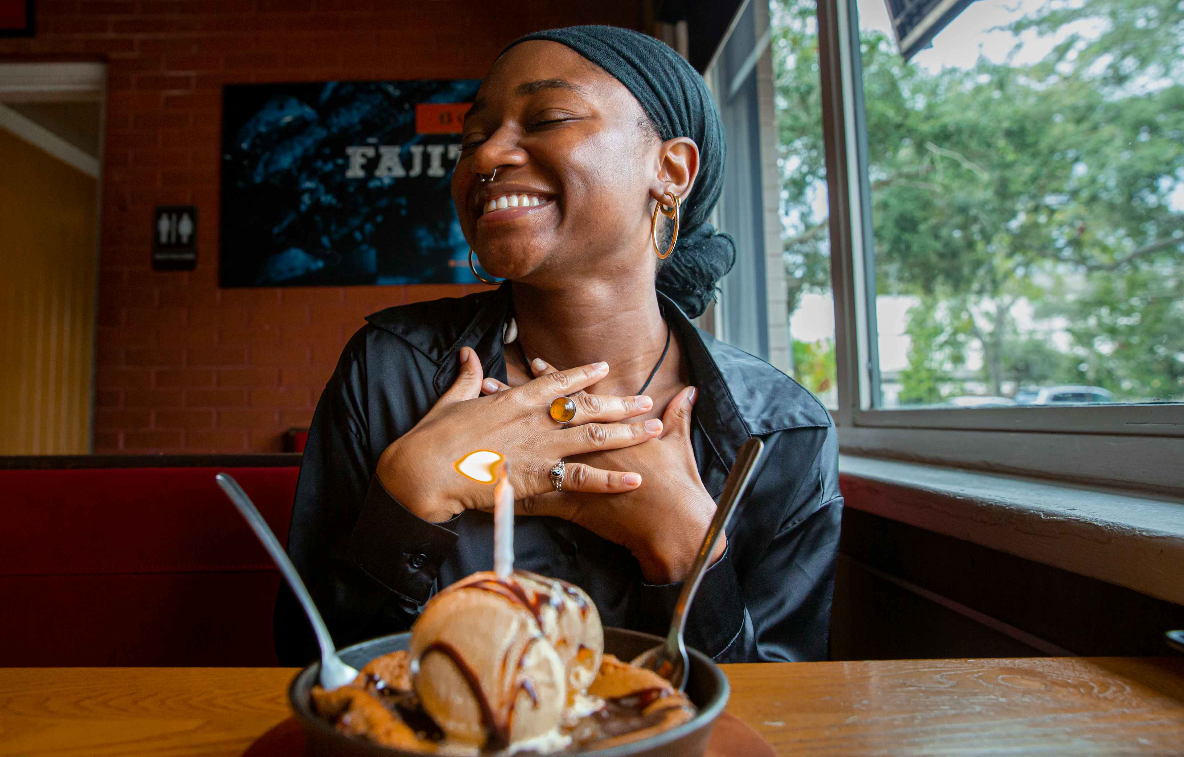 Person smiling looking away with their hands on their chest. in front of them is the Chili's cookie skillet dessert