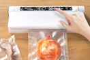 a hand touching a button on a vacuum sealer machine
