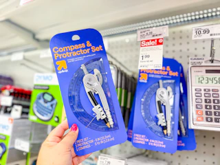 hand holding a up & up compass and protractor set in front of target shelf