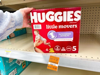 person grabbing a box of huggies diapers from a shelf