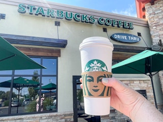 person holding a large starbucks hot beverage outside starbucks