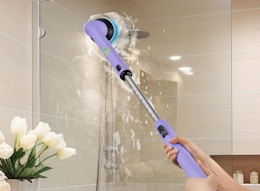 a person using a spin scrubber to clean a shower stall 