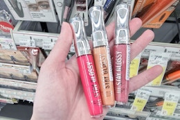 person holding 3 rimmel lip glosses