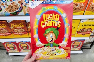 hand holding a box of general mills lucky charms cereal at kroger