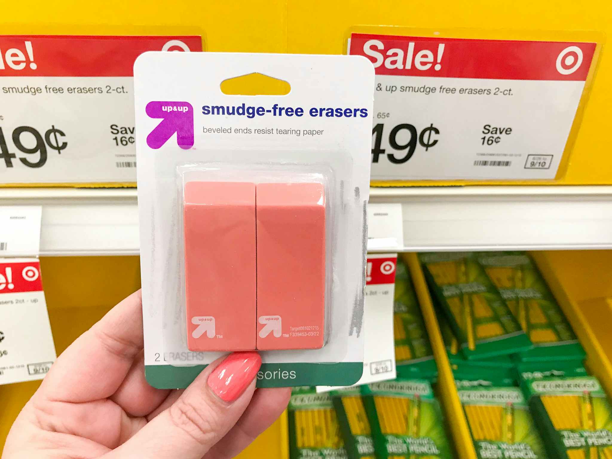 a woman's hand holding up a two-pack of up & up smudge-free erasers in front of a $0.49 sale sign