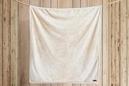 Beige Eddie Bauer Throw Blanket hung up on rope in front of wood panels