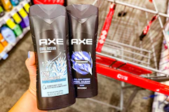person holding 2 bottles of axe body wash over a cvs cart