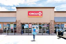A person walking outside of a Circle K convenience store and gas station.